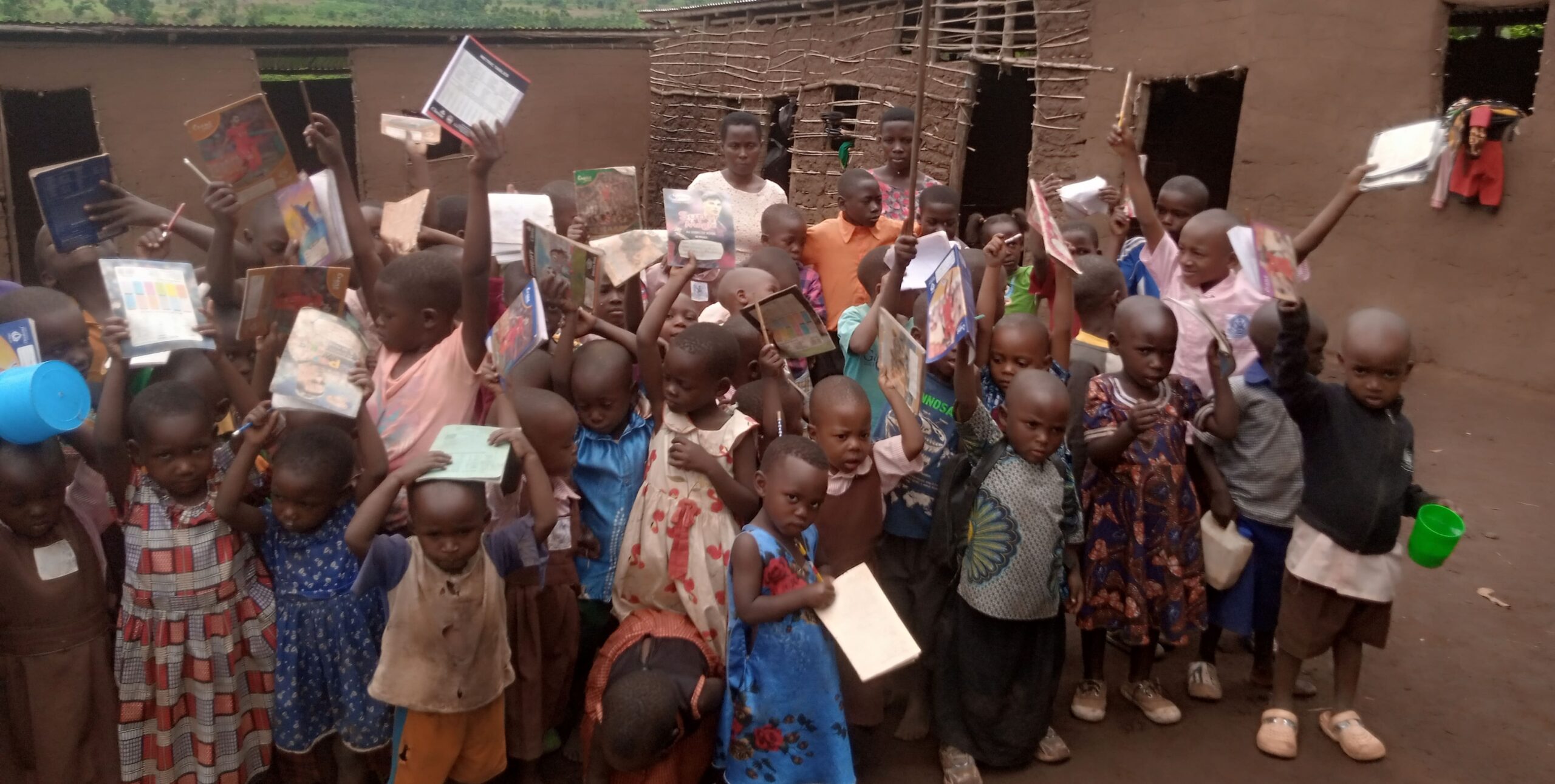 Children in Kifumbira holding books and learning materials