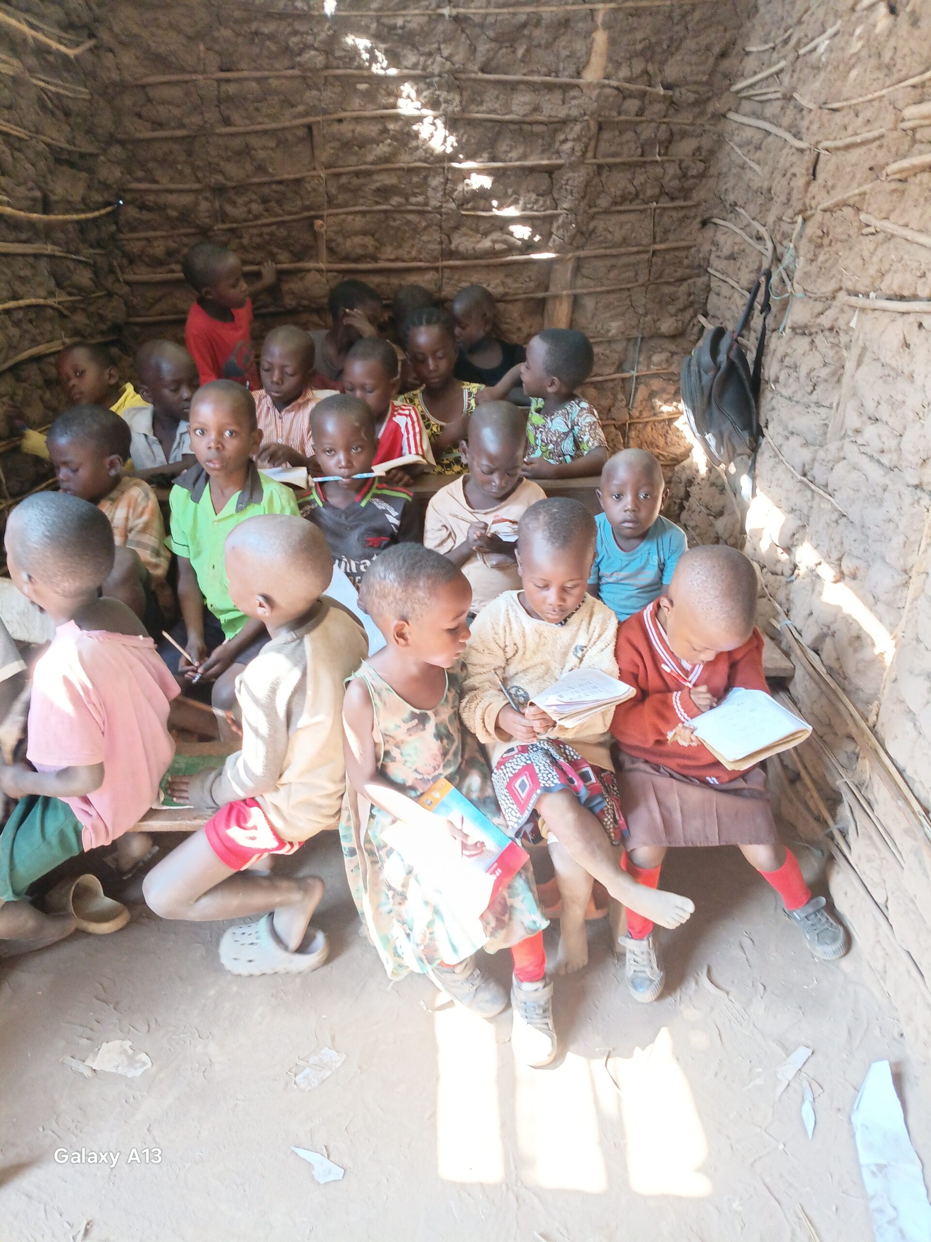Children sitting together and studying from their books in a simple rural classroom in Kifumbira, Uganda