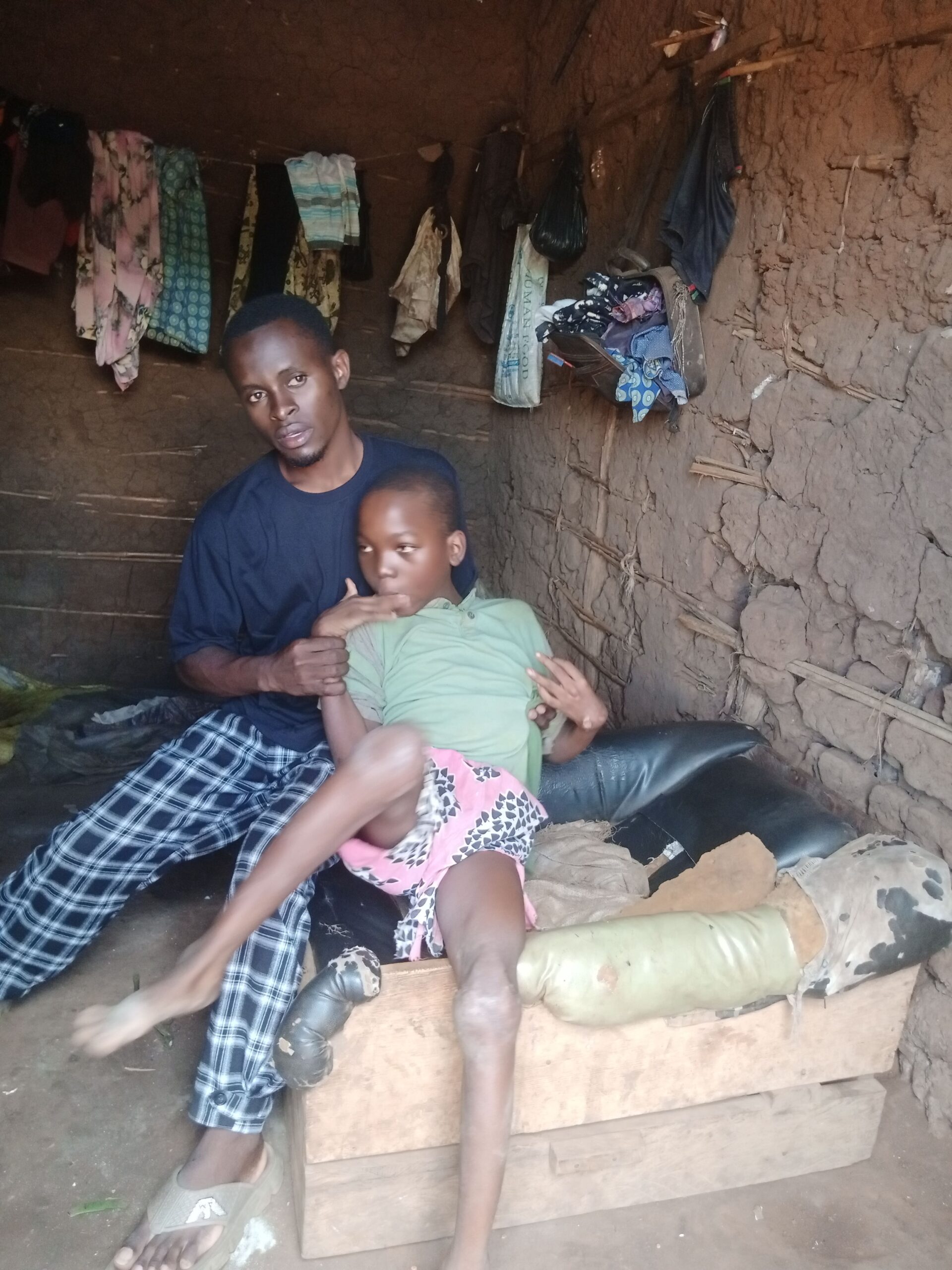 A child sitting with an adult caregiver in Kifumbira, Uganda